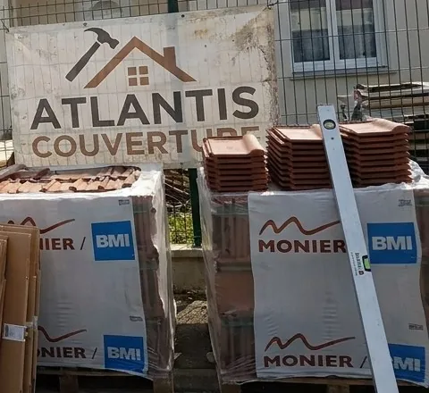 Bâche Atlantis Couverture sur la clôture d'un chantier de toiture à Saint-Herblain, palettes de tuiles neuves